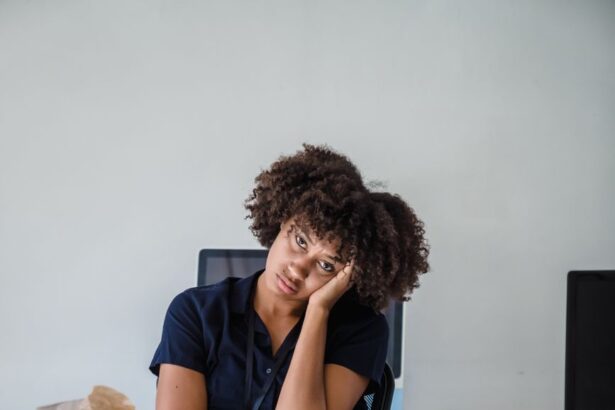 A bored, tired office worker sitting at a cluttered desk, putting off her tasks